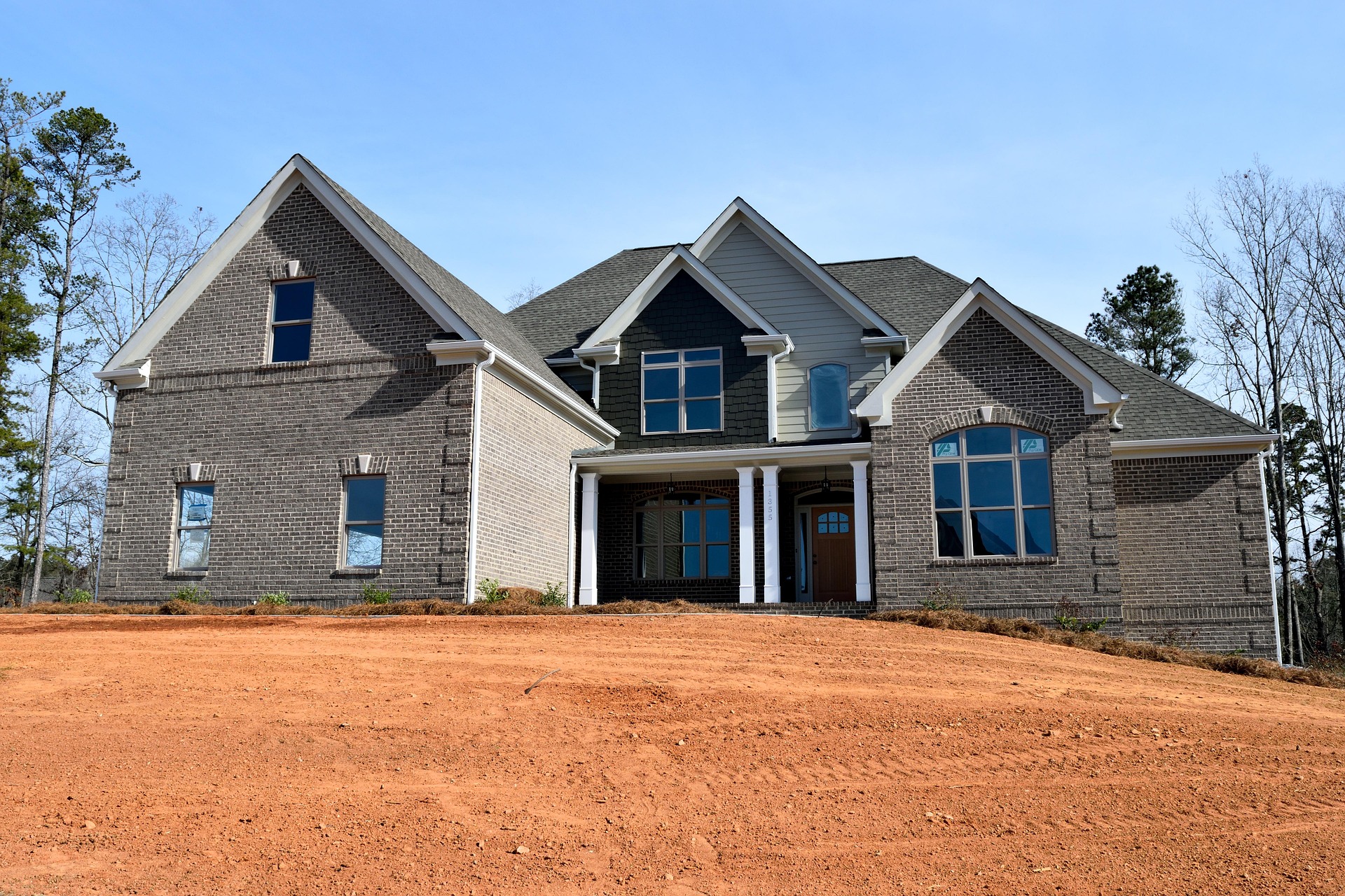 A homeowner reviewing roofing material samples with a contractor while standing in front of a residential home under a clear sky.